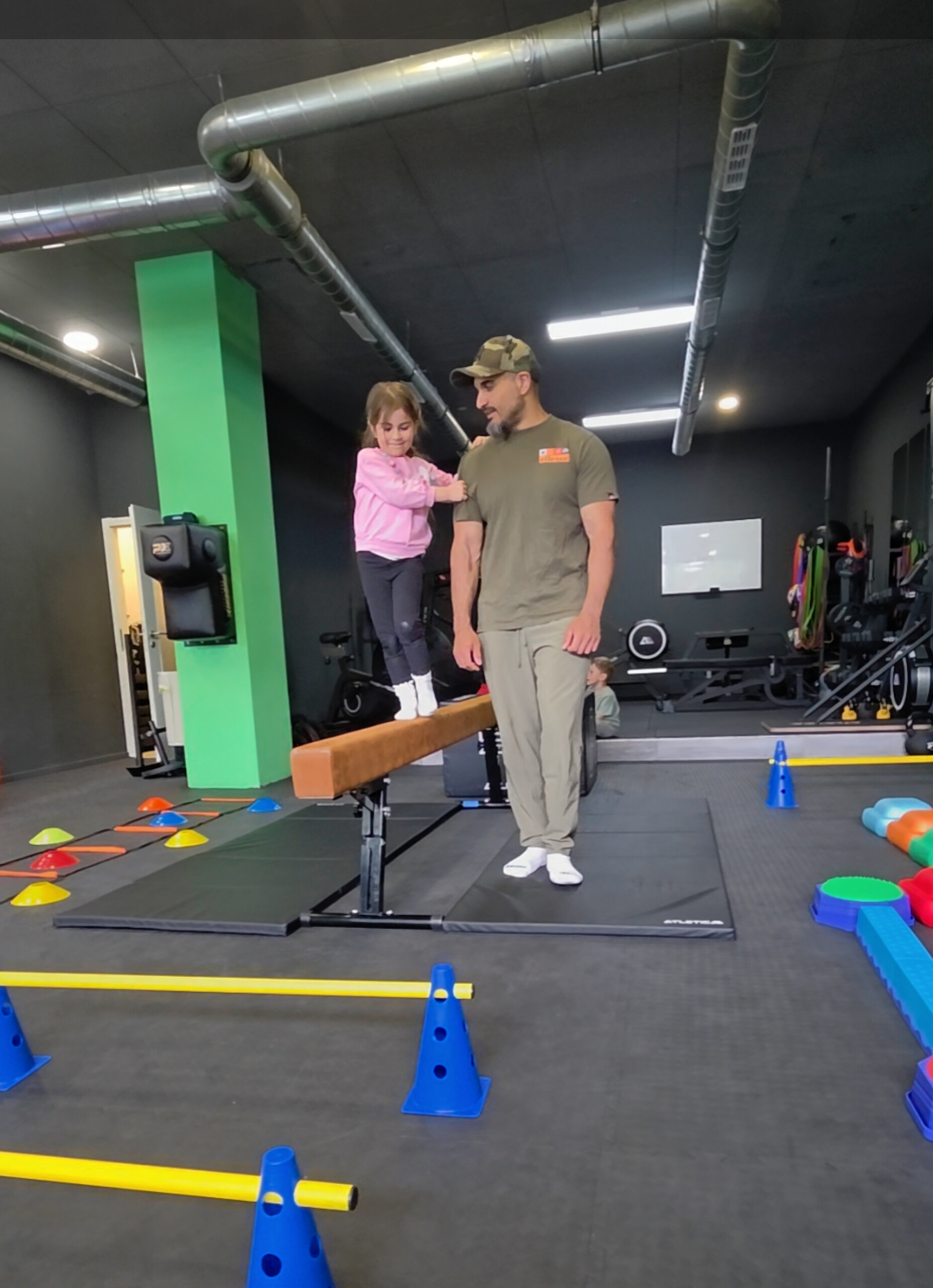 Kind auf dem Schwebebalken mit Coach