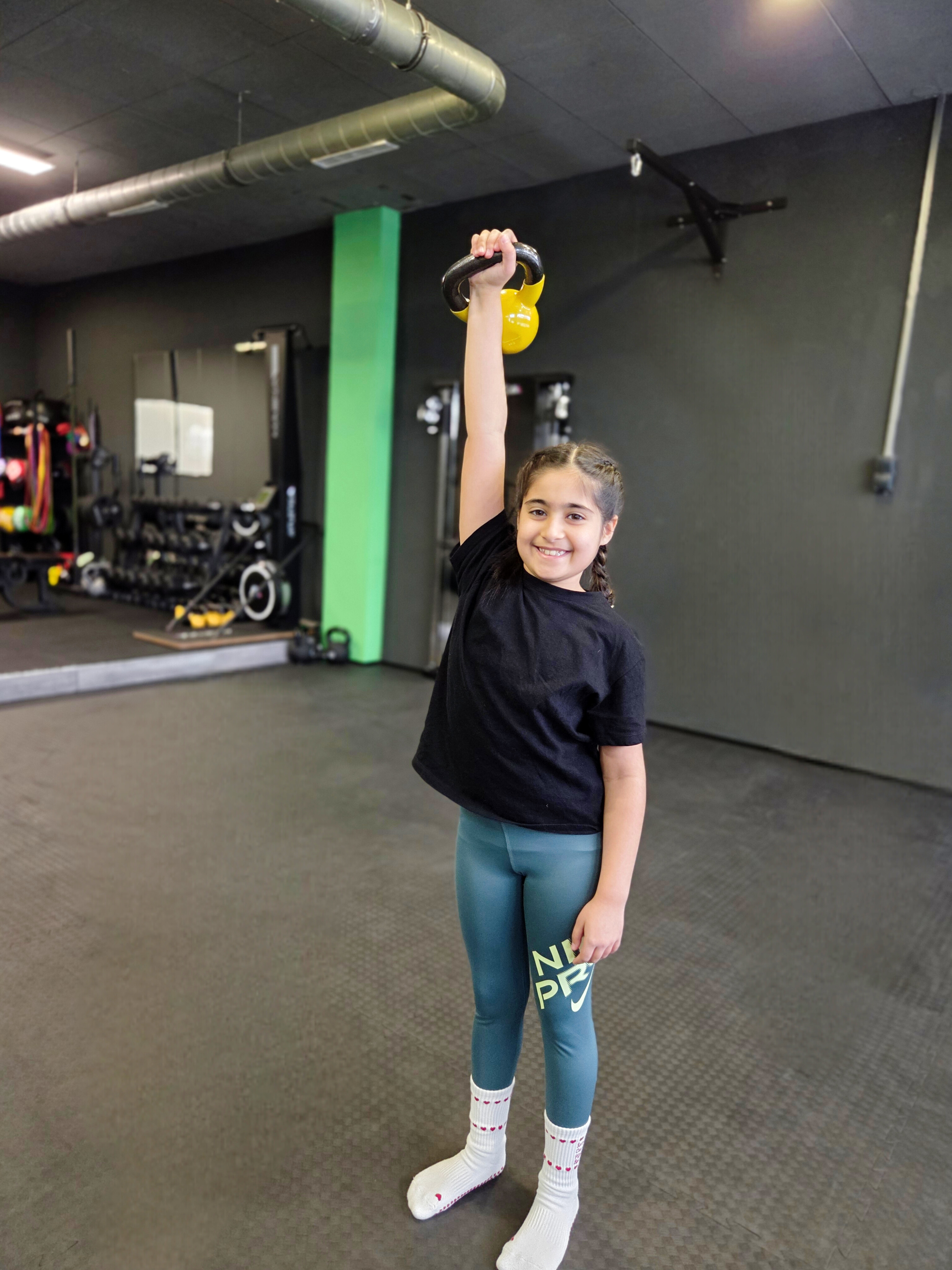 Mädchen stemmt Kettlebell über Kopf